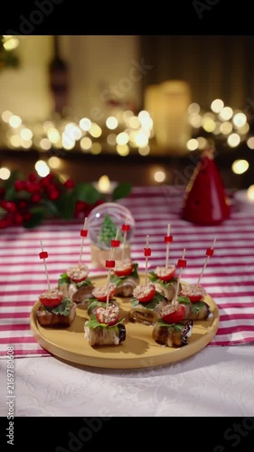 Hands are placed on a table a beautiful plate with small snacks on skewers. Preparing for Christmas dinner, the atmosphere is festive, New Year's Eve - candles, garlands, decorations.