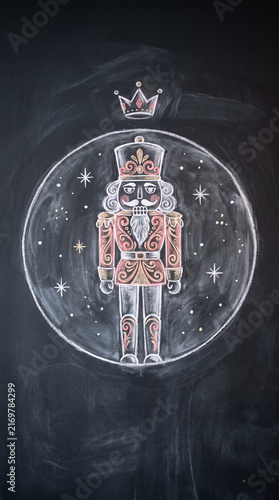 Chalkboard drawing of an ornate nutcracker figurine inside a glowing circle with stars and a crown symbol for a festive holiday seasonal decoration