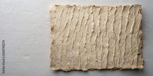 Textured Handmade Paper Sheet with Irregular Edges on a Light Gray Surface