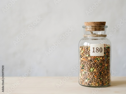 Glass Jar with Colorful Dried Seeds on Wooden Table Background