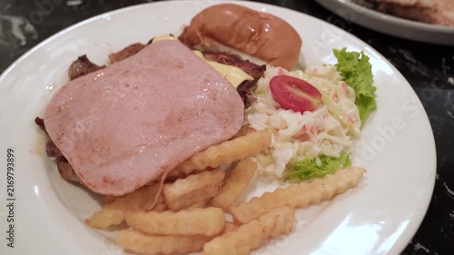 Chicken chop topped with a slice of ham and melted cheese, served with crispy French fries and creamy coleslaw, lettuce, and tomato.