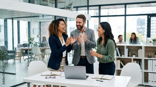 Diverse team celebrating success in modern office, clapping and laughing together.