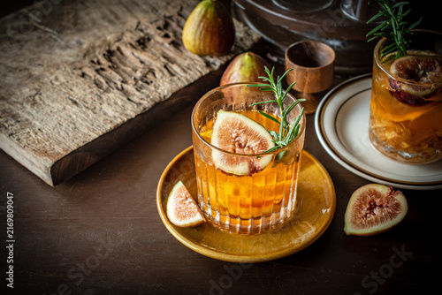 Foto Craft fig cocktail garnished with fresh rosemary sprig and sliced fig in a glass on a dark rustic table