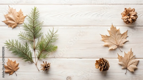 Serene autumnal arrangement featuring dried leaves, pine cones, and evergreen sprigs on a rustic white wooden surface, creating a minimalist nature-inspired composition.