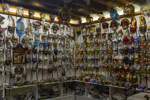 View of a wide collection of traditional Venetian masks displayed on a wall in a shop in Venice, Veneto, Italy.