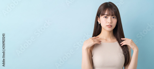 Obraz na płótnie ベージュのリブタンクトップを着て髪に両手を添え微笑む女性