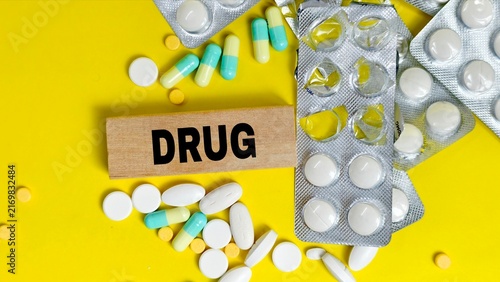 Wooden block with drug text surrounded by pills.