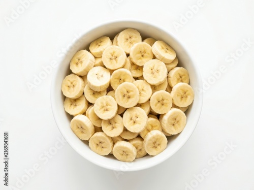 Fresh sliced banana pieces in a white bowl isolated on white background
