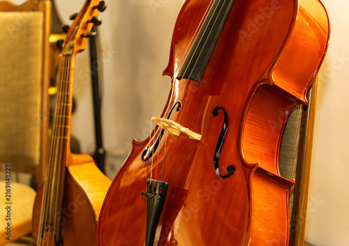 Canvas Print Classical cello and viola da gamba resting against chairs in a music studio