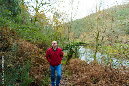 Quadro su tela Man walking forest path contemplating nature by river