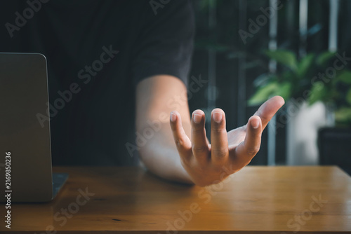 Male hand showing empty palm gesture on office desk with computer. Tech innovation, presenting product, digital mockup and virtual future business concept. AI or hologram concept.