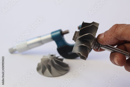 Photography Mechanic hand holding car turbocharger turbine wheel shaft with outside micrometer and compressor impeller on white background