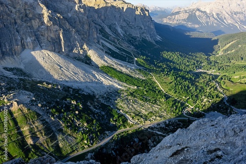Steep scree slopes and green terraces seen from high on a Dolomite ridge above a valley. Aerial style mountain terrain and geology for hiking, travel and outdoor education themes