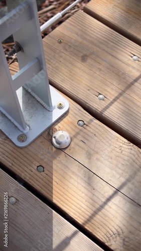 Close up of a modern wooden boardwalk in vertical format, featuring light coloured wood and brushed metal hardware.