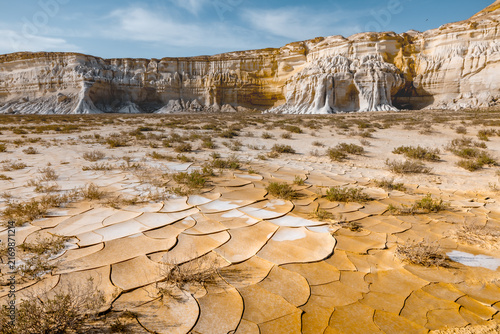 View of the dramatic white limestone cliffs and cracked dry earth of the Tuzbair salt flats in Mangystau District, Mangystau Region, Kazakhstan.