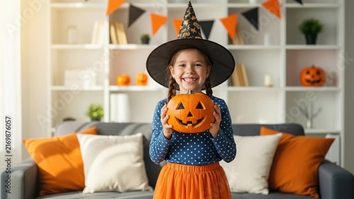Little girl in a witch hat holding a jackolantern