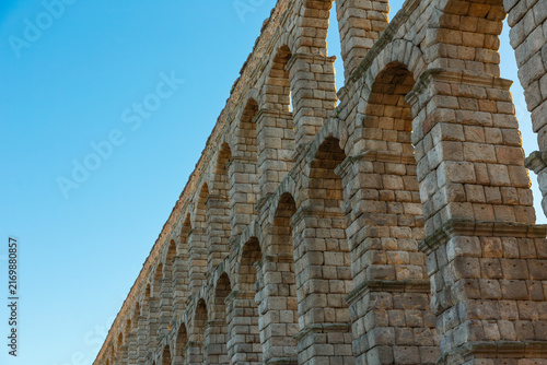 Bild auf Leinwand Low-angle view of the Roman aqueduct in Segovia against blue sky