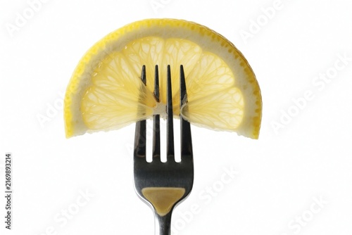 Bright lemon slice impaled on metal fork, presented on clean white backdrop. Translucent texture, vibrant hue suggest freshness, natural goodness. Simplistic yet striking composition for visual