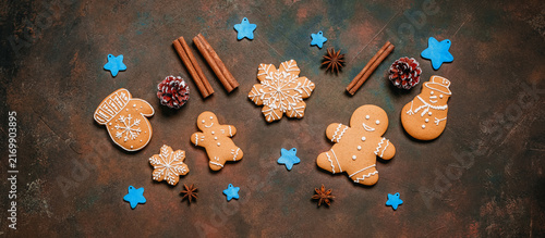 Christmas homemade gingerbread cookies on dark rustic background, gingerbread man, snowman, mitten, snowflakes, top view, flat lay, banner