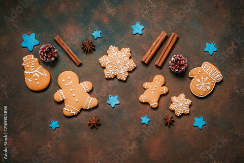 Christmas gingerbread cookies with spices and blue wooden stars on dark grunge background, gingerbread men, top view, flat lay.