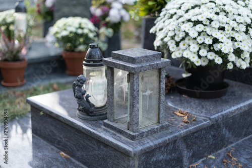 Fotografía tombstone with memorial candle and chrysanthemum in the cemetery
