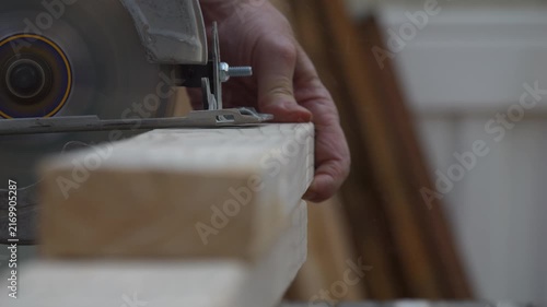 A carpenter cutting a board with a power saw - close up