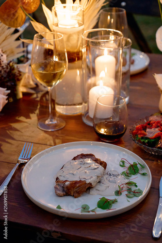 Foto Romantic candlelit dinner featuring a steak topped with creamy mushroom sauce, w
