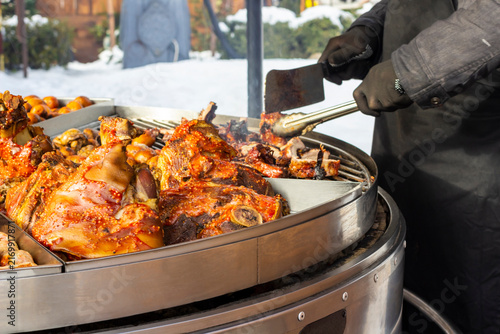 Pieces of grilled meat outdoors. Hands in gloves take pieces of meat with tongs
