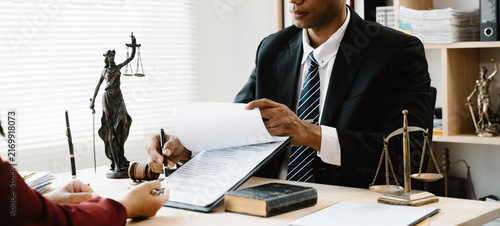 Foto Legal Consultation: Two professionals sit at a desk, carefully reviewing and signing legal documents
