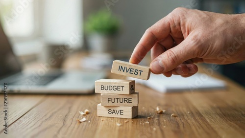 Hand arranging wooden blocks with invest text for financial planning and future budget control.