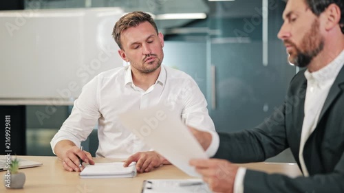 Business professionals engage in focused discussion, reviewing important documents in modern office meeting. Professional collaboration on paper, planning and analyzing strategies.