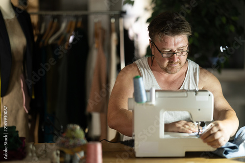 Fotografía Middle-aged male dressmaker working with sewing-machine at night