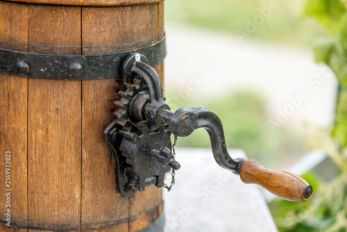 Canvas Print Close-up of an old wooden churn featuring a cast-iron hand crank and a wooden handle