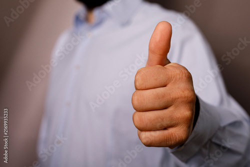 Konstfotografi Close up of a man wearing a light blue shirt giving a thumbs up.