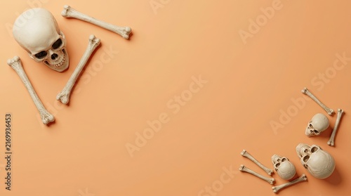 Top view of human skulls and bones arranged on a plain orange background for a halloween celebration