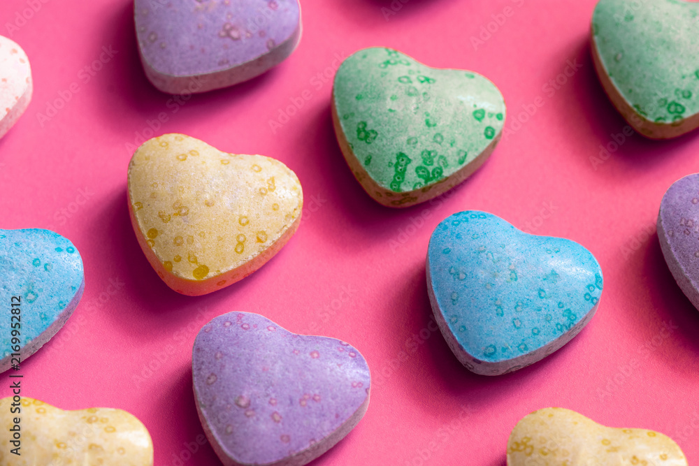 Obraz premium Macro shot of heart shaped colorful candies on pink background