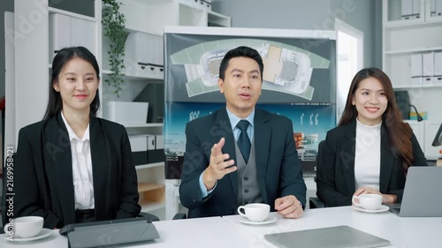 Professional business team discussing an architecture and construction project during a meeting in a modern office. Male manager presenting ideas while two female colleagues listen with documents and 