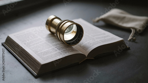 Antique magnifying glass resting on an open book on a wooden table  