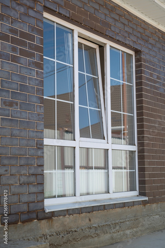 Installation of new panoramic plastic windows. Construction of a dark brown brick house with plastic windows.