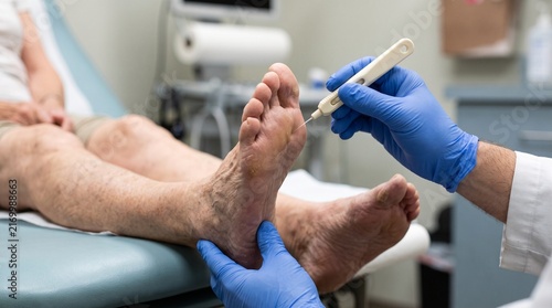 Quadro su tela Close up of doctor's hands testing sensation on elderly patient's bare feet with