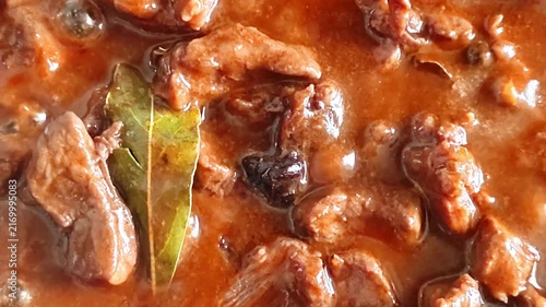Slow cooking beef stew with rich gravy and bay leaf in a pan, close-up