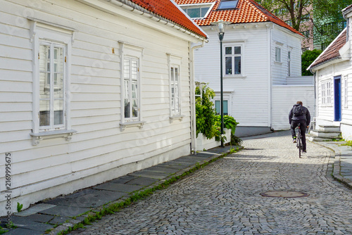 Bild auf Leinwand Cyclist riding cobblestone street through Gamle Stavanger historic wooden houses