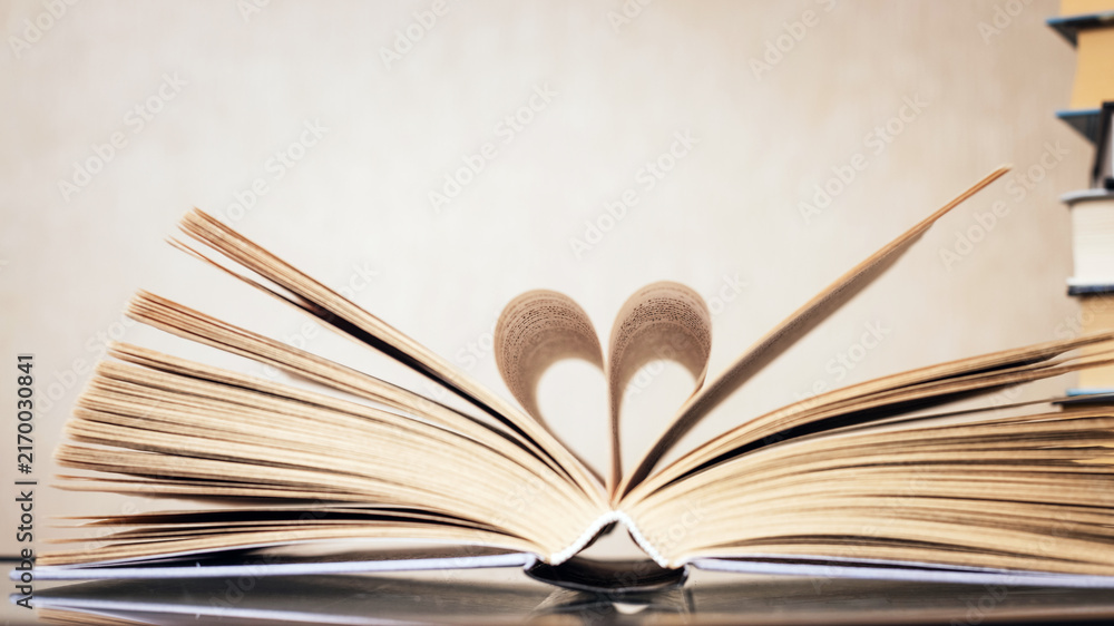 Fototapeta premium Open book on dark wooden surface, minimalist still life.