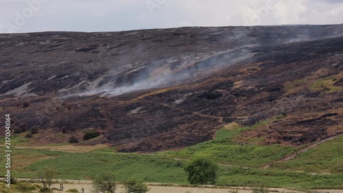 Smoke drifting across scorched moorland slope after wildfire, Llangynidr Moors, Brecon Beacons, Wales, wide view of burnt landscape