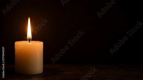 Glowing Candle Flame Flickering Gently Against Dark Black Background with Wide Copy Space, Warm Peaceful Atmosphere