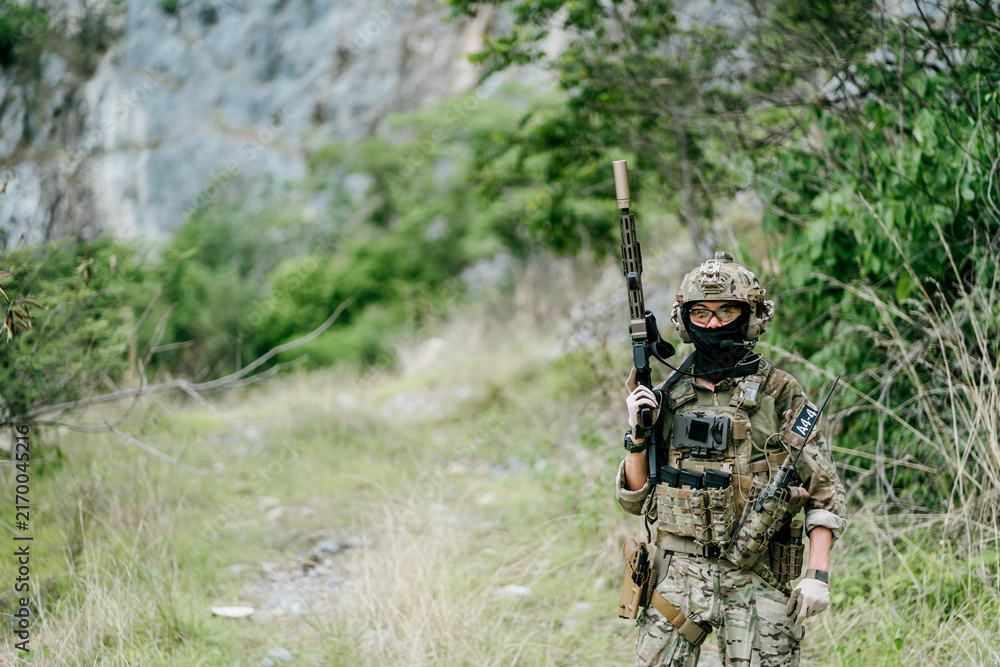 Naklejka premium Focused outdoor soldiers patrol wild jungle during their long term on duty with serious expression and tactical gear ready