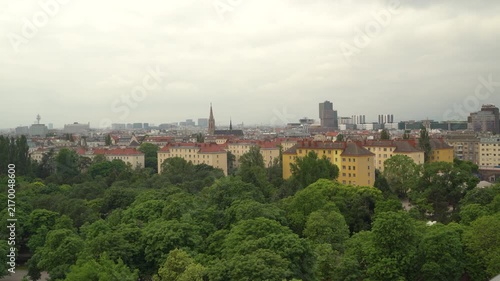 4K video of Vienna, Austria cityscape showing colorful residential buildings, green trees, and historic church spires. Aerial view of European city architecture and urban landscape.
