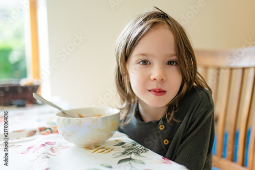 Принти на полотні Young child sitting at a dining table and looking reluctant to eat his meal