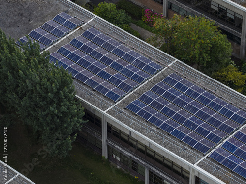 Aerial view of the solar panel array installed on the flat roof of the University of Galway Research and Innovation Centre, surrounded by green trees in Galway, County Galway, Ireland.
