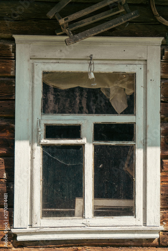 Foto A close-up shot captures an old weathered white wooden window with a cracked pane and a curtain on a rustic dark timber log wall
